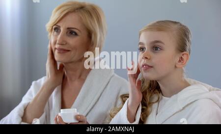 Grandmother And Granddaughter Wrapped In Towels Smile As They