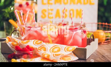 Raspberry lemonade garnished with fresh lemon and raspberries in drinking mason jars. Stock Photo