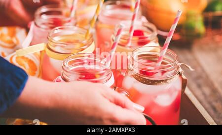 Raspberry lemonade garnished with fresh lemon and raspberries in drinking mason jars. Stock Photo