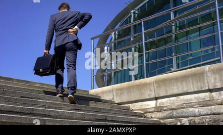 Business man in suit suffering back pain, slipped disc, neurology problems Stock Photo