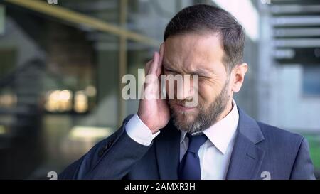 Middle aged businessman suffering strong headache, stressful job, busy lifestyle Stock Photo