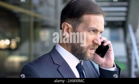 Middle aged boss talking on mobile, serious talk, confidence and determination Stock Photo