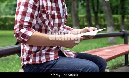 Casual man reading newspaper in park, spending leisure time, carefree weekend Stock Photo