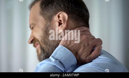 Office employee suffering from neck pain, working in front of computer, spasm Stock Photo