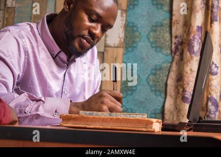 two young black business men in an office, one of them writing on a document Stock Photo