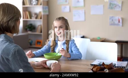 Cheerful daughter and mother having pleasant breakfast together, morning Stock Photo