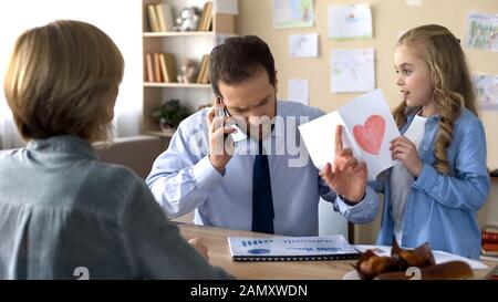 Busy father talking on phone, ignoring loving daughter, paternal indifference Stock Photo