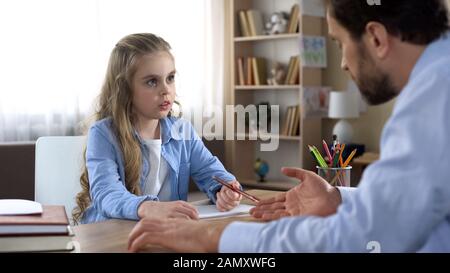 Demanding father making his little daughter doing homework, home schooling Stock Photo