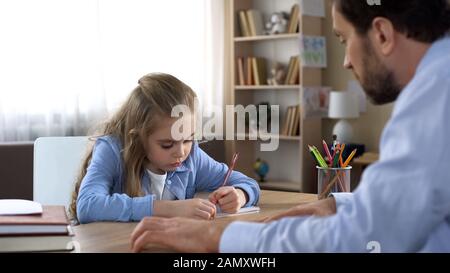 Caring father helping his little daughter doing homework, home schooling Stock Photo
