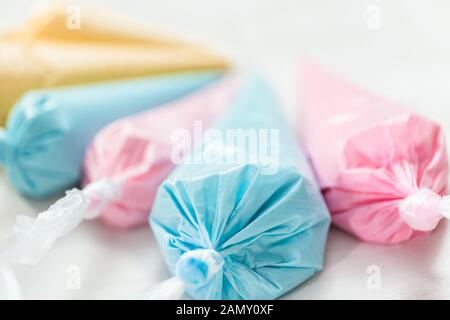 Piping bags with pastel color royal icing to decorate Easter sugar cookies. Stock Photo