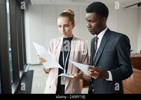 Business couple standing with documents and discussing them together at office Stock Photo