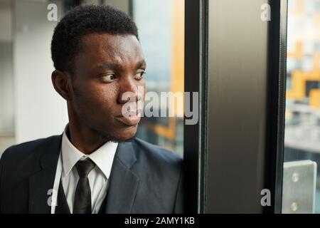 Close-up of pensive African businessman looking through the window at office Stock Photo