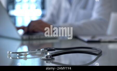 Professional doctor working on laptop in lab, stethoscope on table, medicine Stock Photo