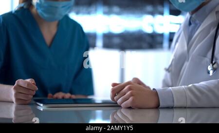 Two doctors checking test results on tablet and discussing patient diagnosis Stock Photo
