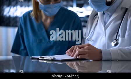 Two young doctors looking at patient medical records and discussing illness Stock Photo