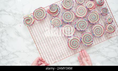 Step by step. Flat lay. Cooling freshly baked bake red, white, and blue pinwheel sugar cookies on a cooling rack. Stock Photo