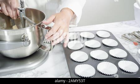 Step by step. Scooping batter with batter scooper into cupcake pan lined  with paper cupcake liners Stock Photo - Alamy