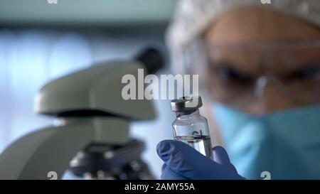Scientist holding in hands bottle with invented vaccine, disease control center Stock Photo