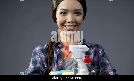 Happy housemaid loves cleaning products, joyfully smiles into the camera Stock Photo