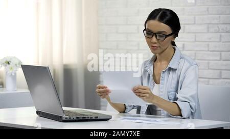 Asian woman in glasses reading letter, subpoena, receipt of correspondence Stock Photo