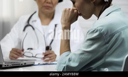 Young patient finds out about incurable disease, female doctor telling bad news Stock Photo