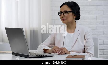 Business woman reading on laptop contract conditions, sitting in private cabinet Stock Photo