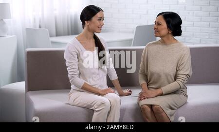 Two female friends communicating, sitting on couch, warm relations between women Stock Photo