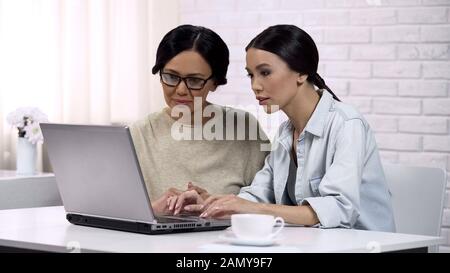 Daughter showing mother how to use laptop, showing online banking services Stock Photo