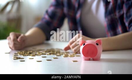 Student pouring out coins from piggy bank, collecting money for vacation trip Stock Photo