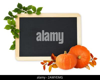 Green leaves and orange pumpkins in a beautiful autumn corner arrangements and a black chalkboard on white background Stock Photo
