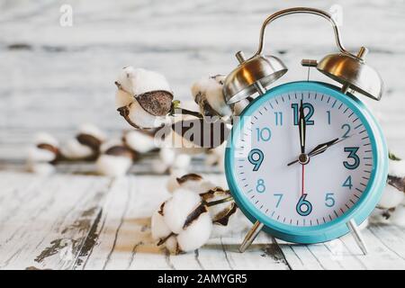 Set your clocks back with this clock iand bolt of cotton over a white wooden table. Daylight saving time concept. Selective focus with blurred backgro Stock Photo