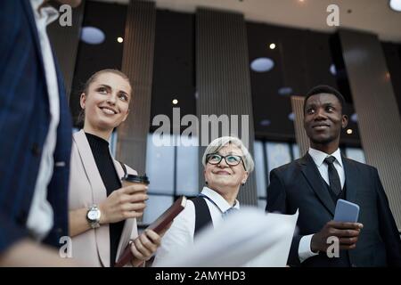 Group of colleagues standing at office hall and preparing for the meeting together Stock Photo