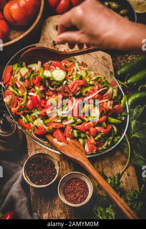 Womans hands adding spices to Turkish Chopard Salad with vegetables Stock Photo