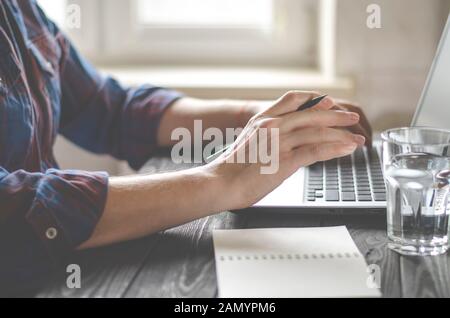 Men's hands with black pencil using laptop in home office Stock Photo