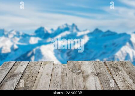 View from empty wooden deck table to the sunny winter mountains Stock Photo
