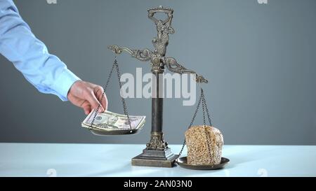 Bread outweighs dollars on scales, poverty concept, rising prices for essentials Stock Photo