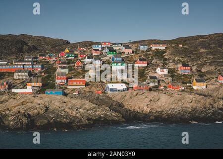 Colorful houses dot the hillsides of the fishing town of Kangaamiut, West Greenland. Icebergs from Kangia glacier in Greenland swimming with blue sky Stock Photo