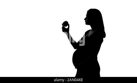 Silhouette of pregnant woman eating apple, healthy diet during pregnancy time Stock Photo