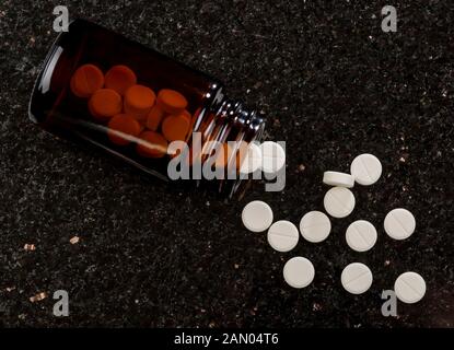 Glass bottle with white round pills. dark textured background Stock Photo