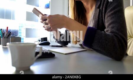 Female office worker reading message smartphone, appointing meeting with client Stock Photo