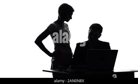 Irritated wife in apron looking at husband working on laptop, household duties Stock Photo