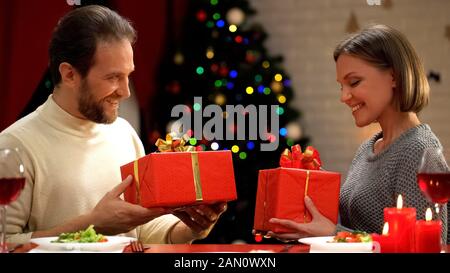 Man and lady exchanging Christmas presents, cozy romantic evening for couple Stock Photo