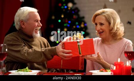 Happy elderly couple exchanging presents, long lasting marriage, Xmas eve Stock Photo