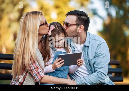 Happy family spending time together in the park.People,nature, and technology concept. Stock Photo