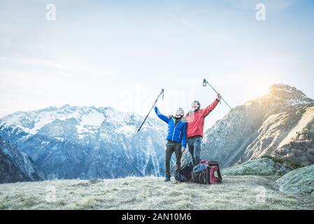 Hiker friends having reached peak of the mountain - Happy men are happy after climbing at sunset - Extreme sport, friendship and survival concept - Co Stock Photo
