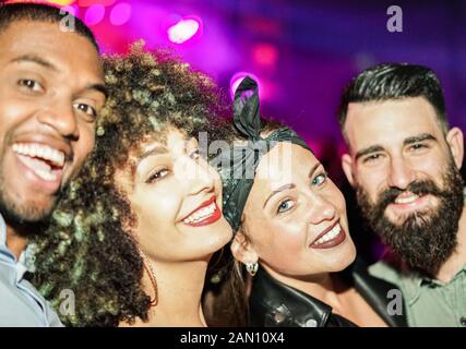 Happy friends taking selfie  in night club dance floor - Young people enjoying weekend nightlife and having fun together - Soft focus on right woman e Stock Photo