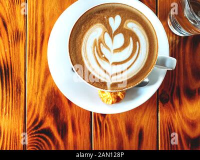 Cup of cappuccino standing on a wooden table, White cup on a plate with cookies, Texture of old wood panels, brown texture background, color, natural Stock Photo