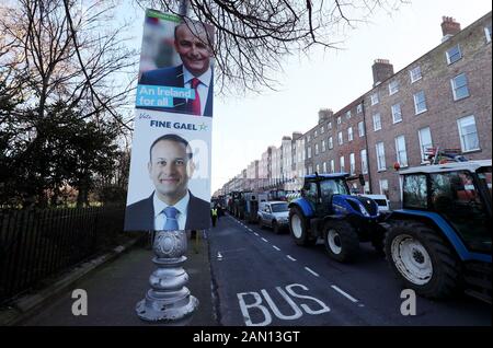 Election posters for leader of Fine Gael Leo Varadkar (bottom) and leader of Fianna Fail Micheal Martin are seen on a lamp post on Merrion Square as tractors are parked around Dublin city centre as a protest by farmers over the prices they get for their produce continues. Stock Photo