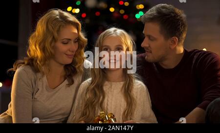 Excited girl holding gift from parents, childish dreams come true at Christmas Stock Photo