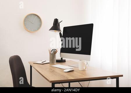 Workplace with computer, chair and cup of coffee on wood table. Clock on wall Stock Photo